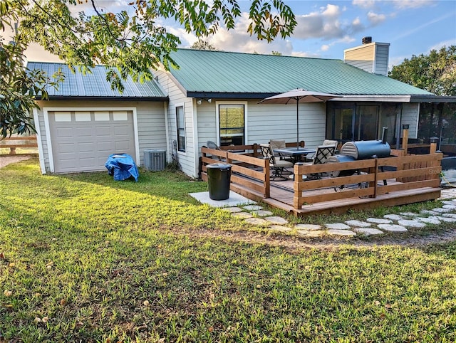 back of property featuring central AC unit, a garage, a deck, and a yard