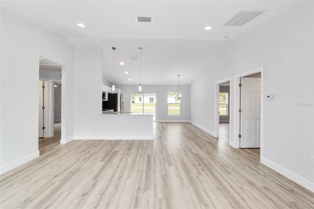 unfurnished living room with lofted ceiling, light wood-type flooring, visible vents, and baseboards