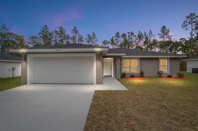 ranch-style house featuring a front lawn, concrete driveway, an attached garage, and stucco siding