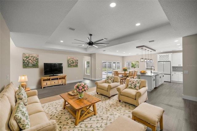 living room with sink, light hardwood / wood-style flooring, and a textured ceiling