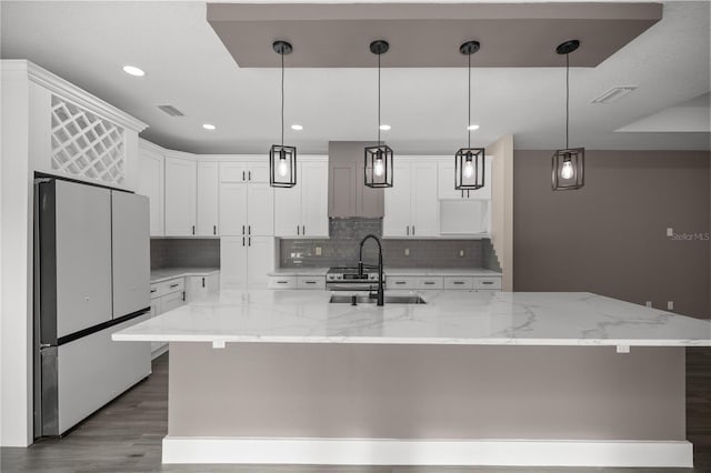 kitchen featuring pendant lighting, white cabinetry, a spacious island, and white refrigerator