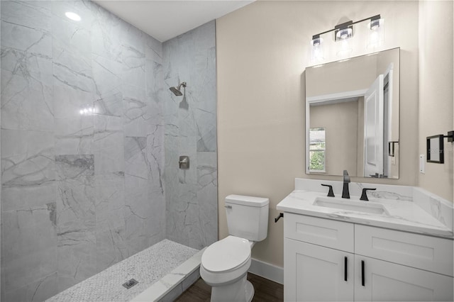 bathroom featuring vanity, toilet, hardwood / wood-style floors, and a tile shower