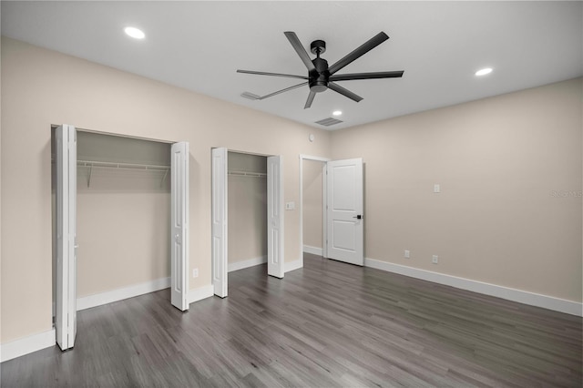 unfurnished bedroom with two closets, dark wood-type flooring, and ceiling fan