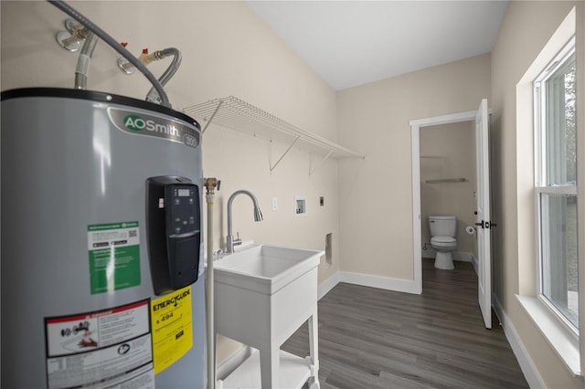 washroom featuring sink, electric water heater, washer hookup, and dark hardwood / wood-style floors