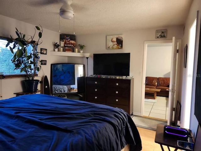 bedroom with ceiling fan, light wood-type flooring, and a textured ceiling