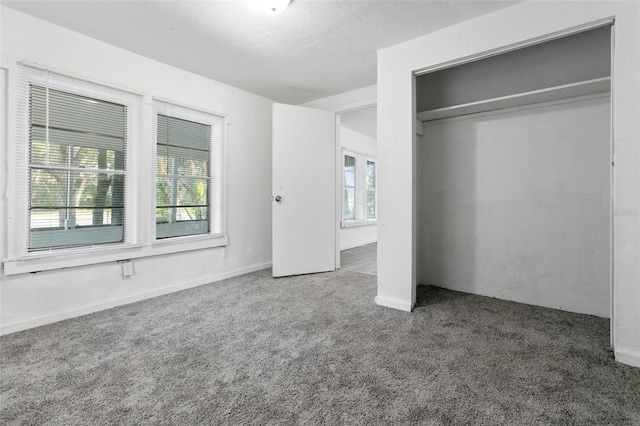 unfurnished bedroom featuring dark colored carpet and a closet