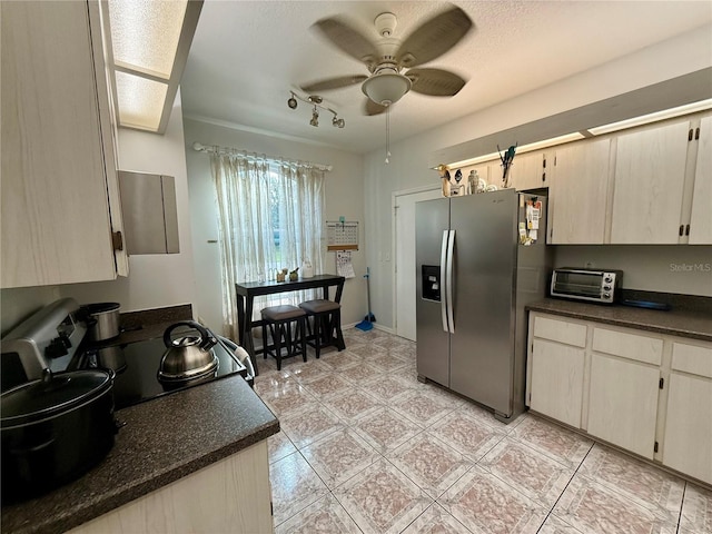 kitchen with a textured ceiling, ceiling fan, light tile patterned floors, and stainless steel appliances