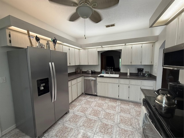 kitchen featuring ceiling fan, sink, stainless steel appliances, and a textured ceiling