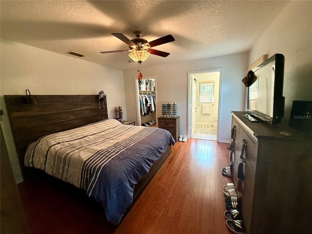 bedroom featuring ceiling fan, wood-type flooring, a textured ceiling, and connected bathroom