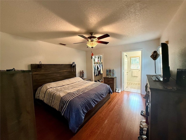 bedroom with wood-type flooring, a textured ceiling, ceiling fan, and connected bathroom