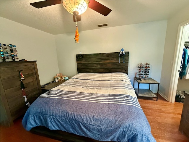 bedroom with hardwood / wood-style floors, a textured ceiling, and ceiling fan