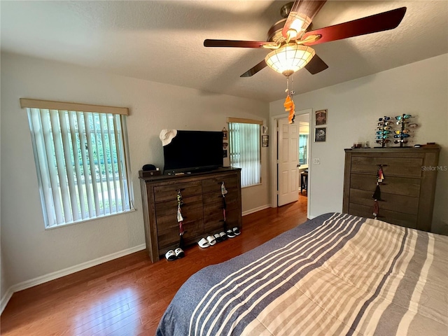 bedroom with a textured ceiling, ceiling fan, and dark hardwood / wood-style floors