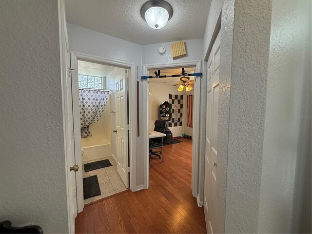 corridor featuring light hardwood / wood-style floors and a textured ceiling