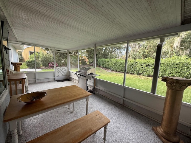 unfurnished sunroom featuring decorative columns, a wealth of natural light, and wood ceiling