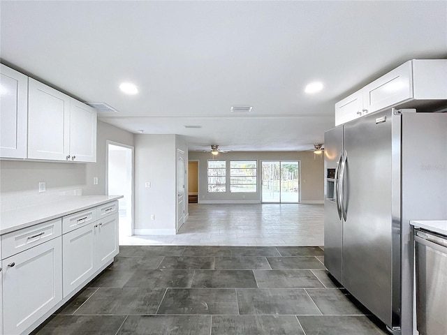 kitchen with white cabinets, ceiling fan, stainless steel fridge, and dark tile patterned flooring