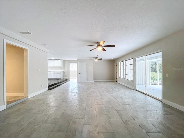 unfurnished living room with ceiling fan and a textured ceiling