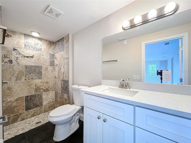 bathroom featuring tiled shower, vanity, and toilet