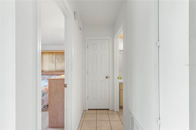 hallway featuring light tile patterned floors and a textured ceiling