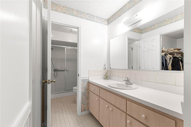 bathroom with tile patterned flooring, a textured ceiling, toilet, a shower with door, and vanity