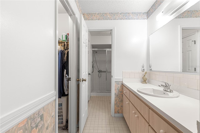 bathroom with tile patterned floors, vanity, a shower with shower door, and a textured ceiling