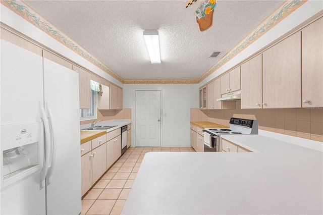 kitchen with decorative backsplash, a textured ceiling, white appliances, sink, and light tile patterned floors