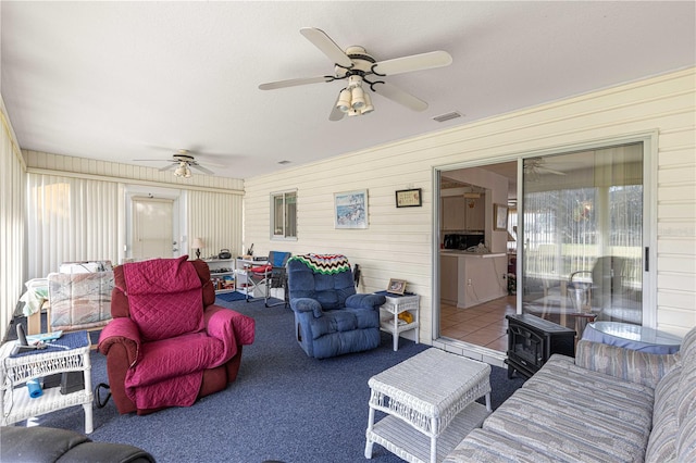 carpeted living room featuring ceiling fan and wooden walls