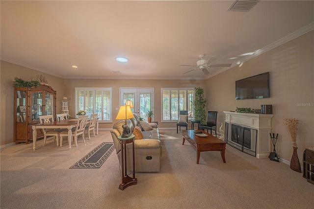 living room featuring crown molding, a glass covered fireplace, visible vents, and light colored carpet