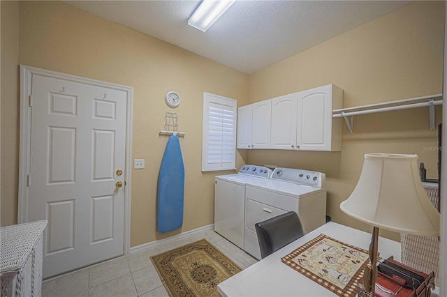 laundry room with a textured ceiling, light tile patterned flooring, baseboards, independent washer and dryer, and cabinet space