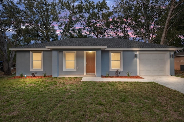 ranch-style home with a garage, a front lawn, concrete driveway, and stucco siding