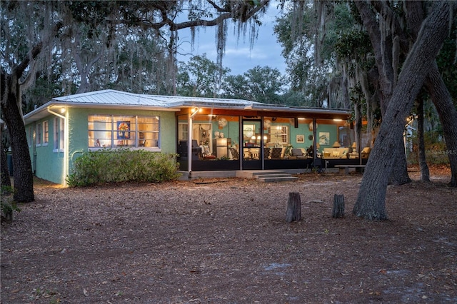 back house at dusk with a sunroom