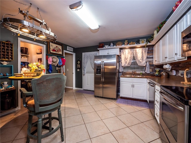 kitchen featuring white cabinets, light tile patterned flooring, sink, and stainless steel appliances