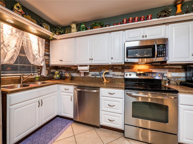 kitchen with sink, decorative backsplash, light tile patterned floors, white cabinetry, and stainless steel appliances