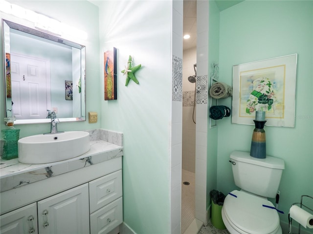 bathroom with toilet, vanity, and tiled shower