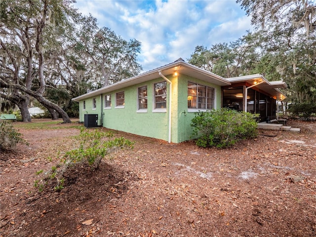 view of property exterior with central AC unit and a sunroom