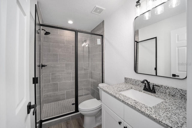 bathroom with vanity, toilet, a textured ceiling, an enclosed shower, and wood-type flooring