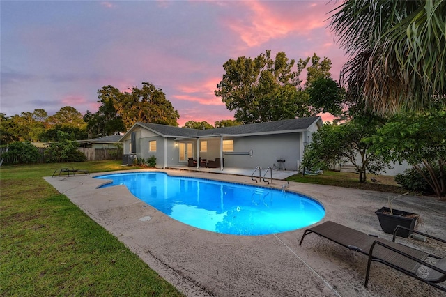 pool at dusk featuring a patio area and a yard