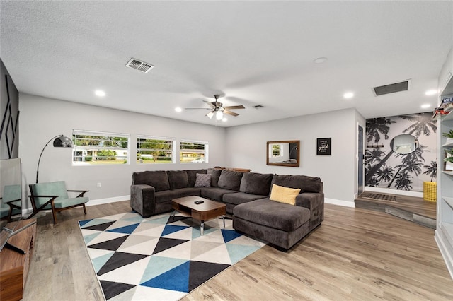 living room with a textured ceiling, light hardwood / wood-style floors, and ceiling fan