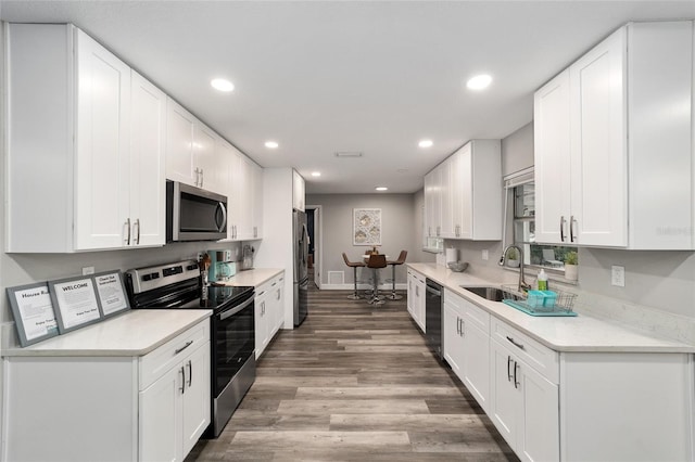 kitchen featuring hardwood / wood-style floors, sink, white cabinetry, and stainless steel appliances