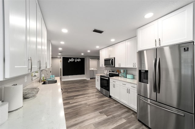 kitchen featuring light stone countertops, stainless steel appliances, sink, hardwood / wood-style flooring, and white cabinets