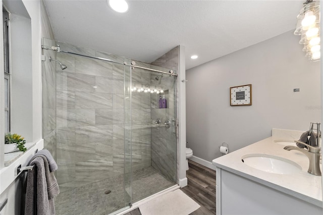 bathroom featuring hardwood / wood-style flooring, vanity, toilet, and a shower with door