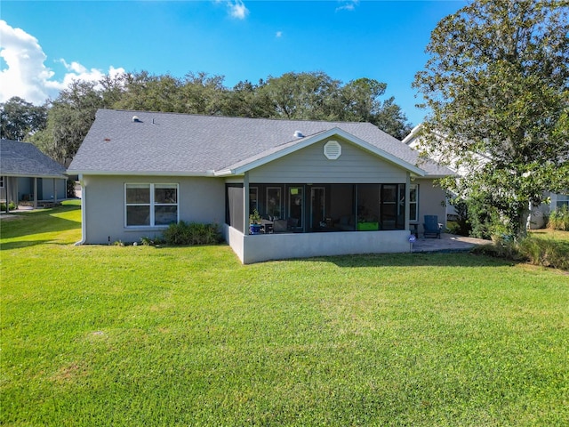 rear view of house featuring a lawn and a sunroom