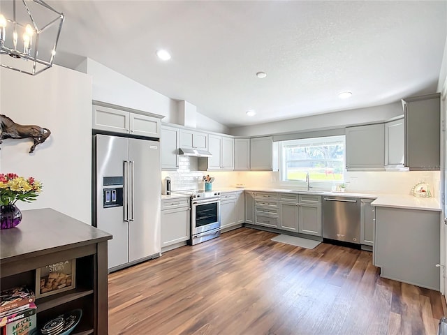 kitchen featuring dark hardwood / wood-style floors, pendant lighting, lofted ceiling, gray cabinets, and appliances with stainless steel finishes