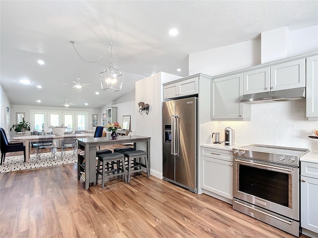 kitchen featuring white cabinets, lofted ceiling, stainless steel appliances, and light hardwood / wood-style flooring