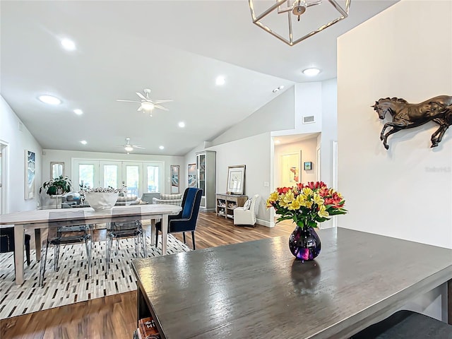 dining room with ceiling fan with notable chandelier, hardwood / wood-style floors, high vaulted ceiling, and french doors