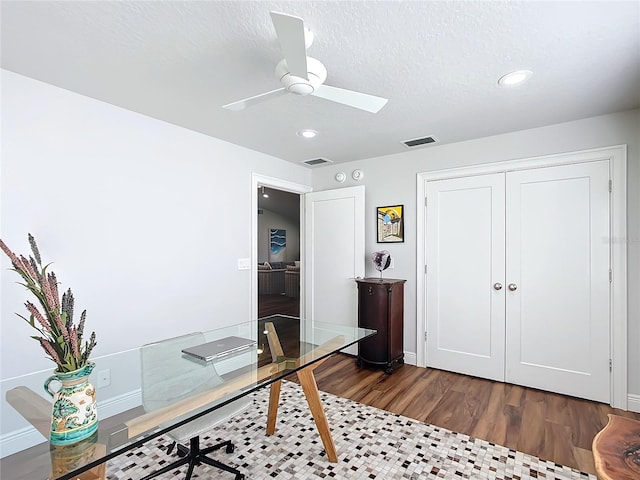 home office with dark hardwood / wood-style floors, ceiling fan, and a textured ceiling