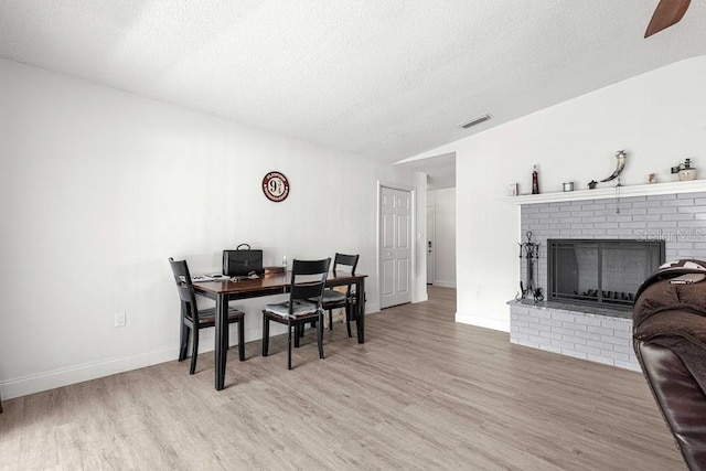 dining room with a fireplace, wood-type flooring, and a textured ceiling