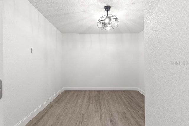 unfurnished room with wood-type flooring and a textured ceiling