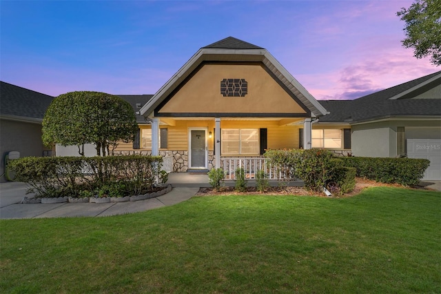 view of front of property featuring a lawn, covered porch, and a garage