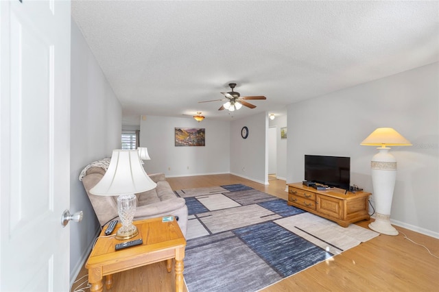 living room featuring wood-type flooring, a textured ceiling, and ceiling fan