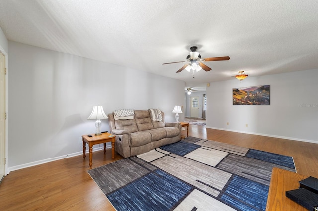 living room featuring hardwood / wood-style flooring, ceiling fan, and a textured ceiling